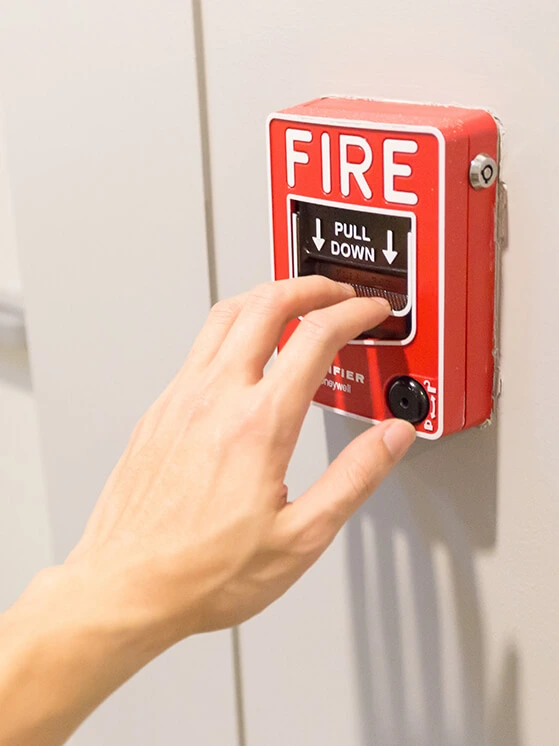 person-pulling-fire-alarm-on-wall